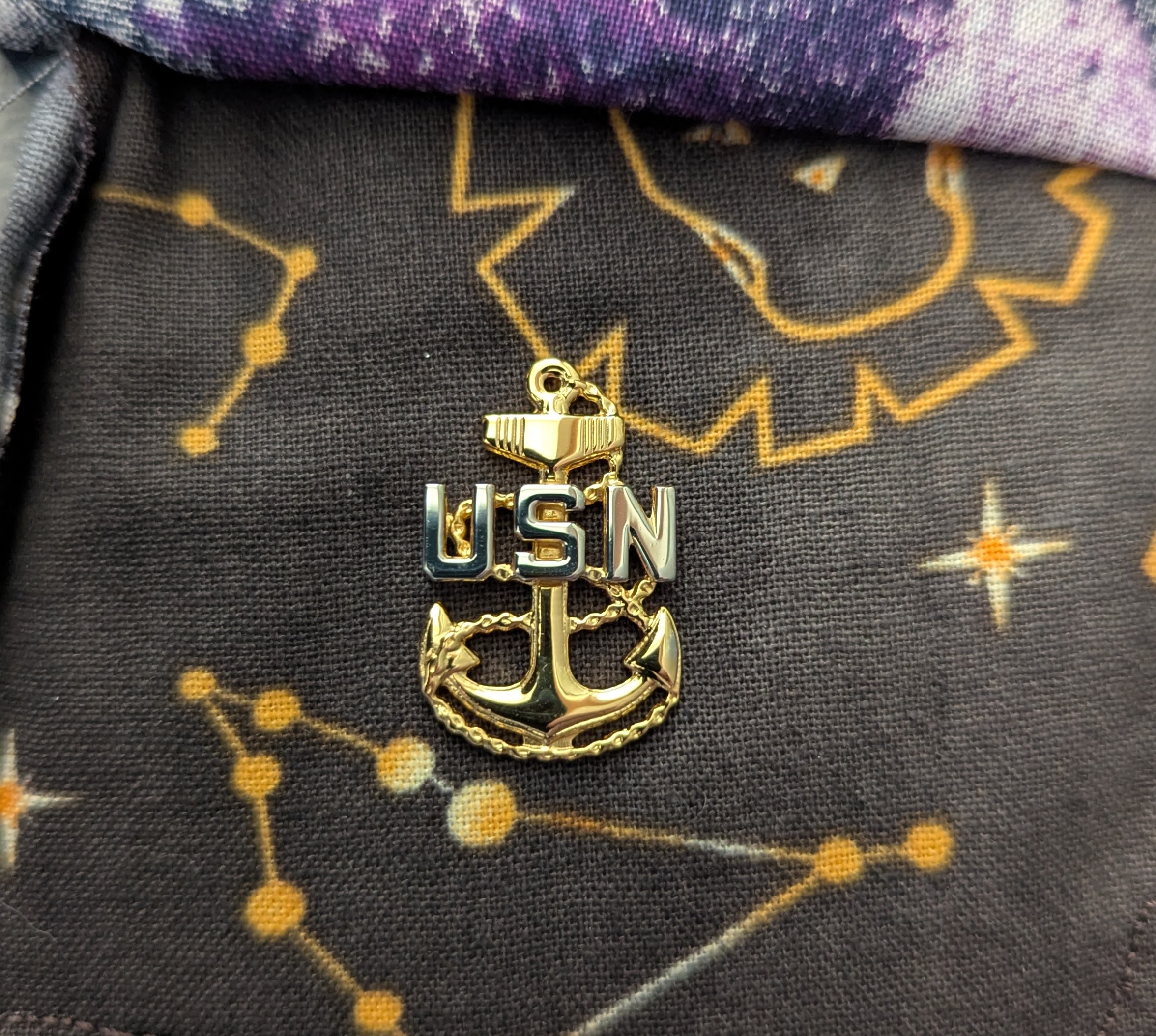 Gold USN anchor insignia resting on patterned fabric inside a pocket
